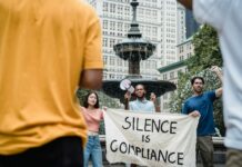 7 Steps to Build a Comment-Centric Social Media Funnel A diverse group of protesters holding a banner and megaphone in a city square advocating for social change.