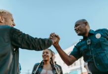 7 Commenting Myths That Are Hurting Your Engagement A friendly handshake between a police officer and a civilian during an outdoor community event.